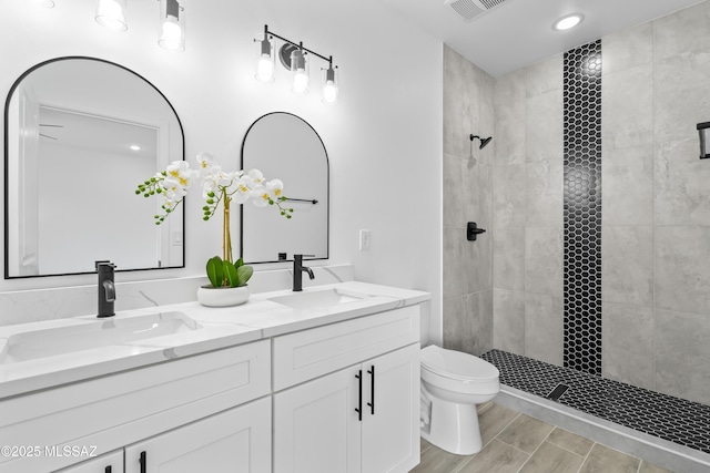 bathroom featuring vanity, toilet, and a tile shower