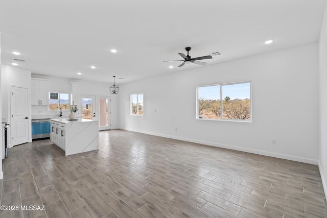 kitchen featuring stainless steel dishwasher, a kitchen island, a wealth of natural light, pendant lighting, and white cabinets