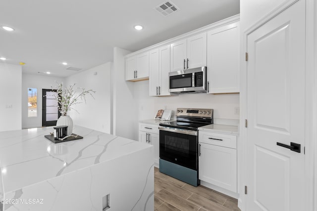 kitchen with light stone countertops, stainless steel appliances, and white cabinets