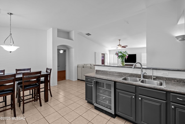 kitchen featuring lofted ceiling, sink, light tile patterned floors, ceiling fan, and beverage cooler