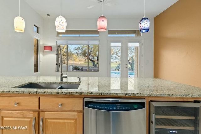 kitchen with sink, dishwasher, wine cooler, light stone counters, and decorative light fixtures