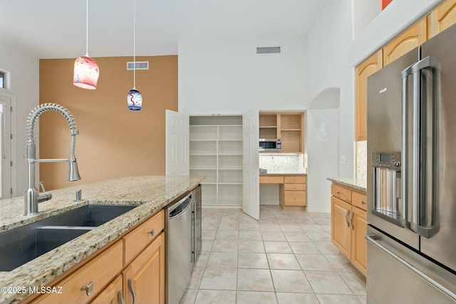 kitchen featuring light stone countertops, appliances with stainless steel finishes, sink, and pendant lighting