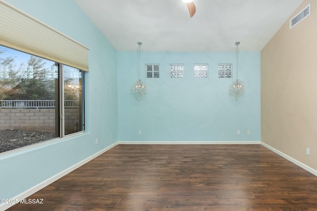 spare room with a notable chandelier and dark hardwood / wood-style floors