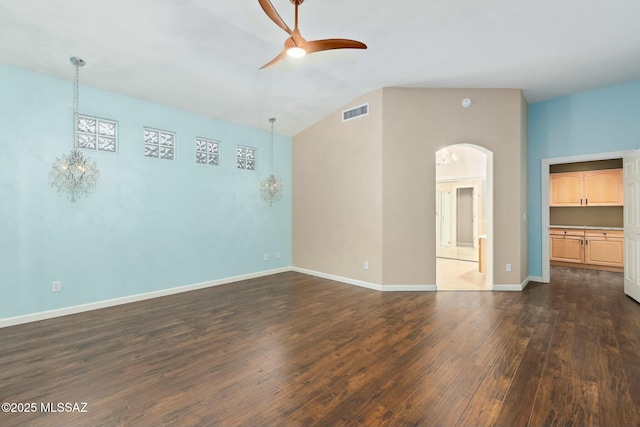 empty room with lofted ceiling, dark hardwood / wood-style floors, and ceiling fan with notable chandelier