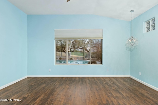 spare room with dark hardwood / wood-style flooring and a chandelier