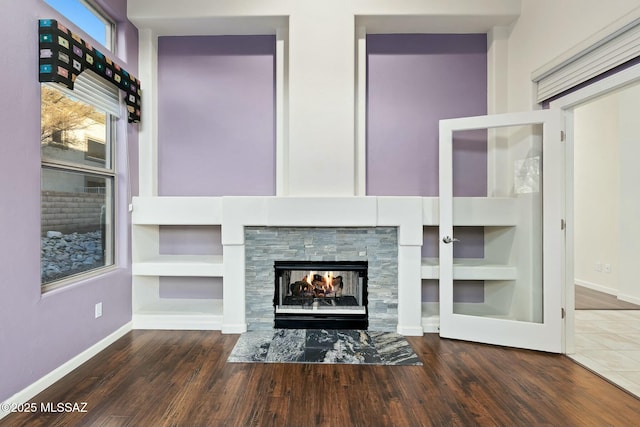 unfurnished living room with built in shelves, dark hardwood / wood-style flooring, and a tiled fireplace