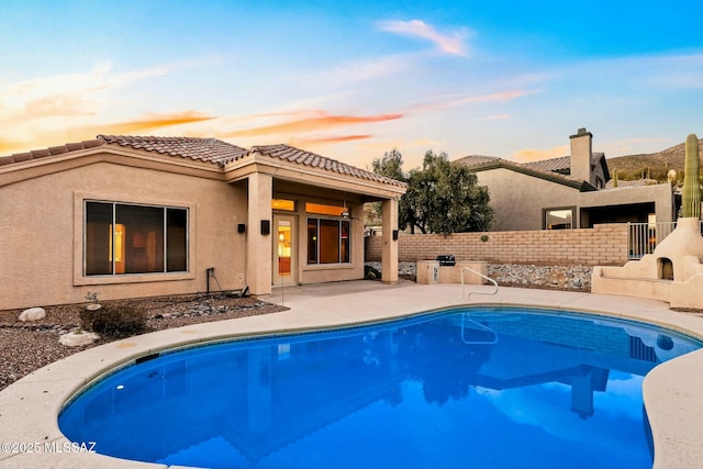 pool at dusk featuring a patio