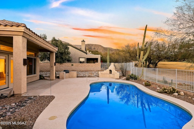 pool at dusk featuring a mountain view and a patio area