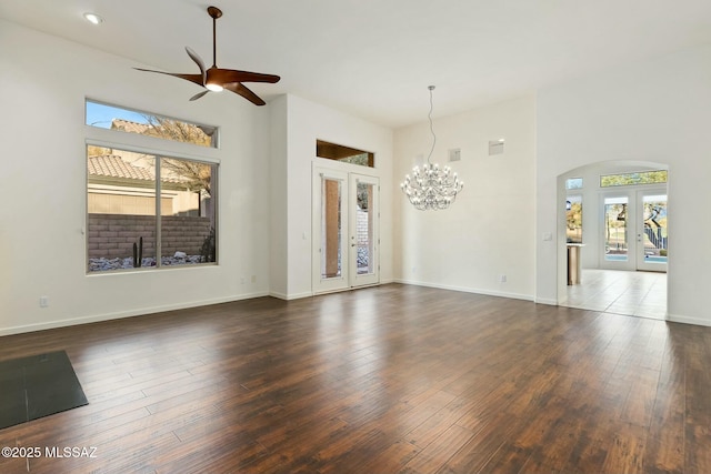 spare room with dark hardwood / wood-style floors, ceiling fan with notable chandelier, french doors, and a high ceiling