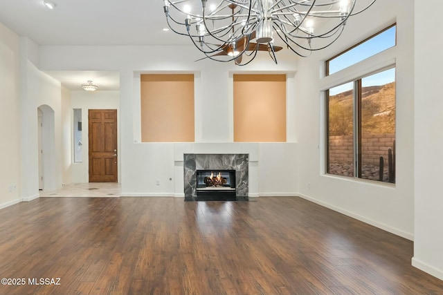 unfurnished living room with a notable chandelier, a fireplace, and dark hardwood / wood-style floors