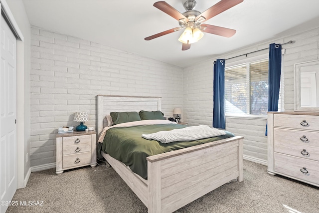 bedroom with brick wall, dark carpet, ceiling fan, and a closet