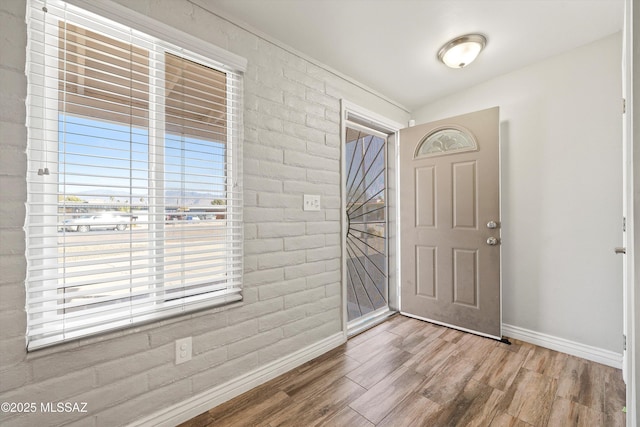 entryway featuring brick wall and wood-type flooring