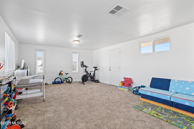 exercise room with carpet floors and brick wall