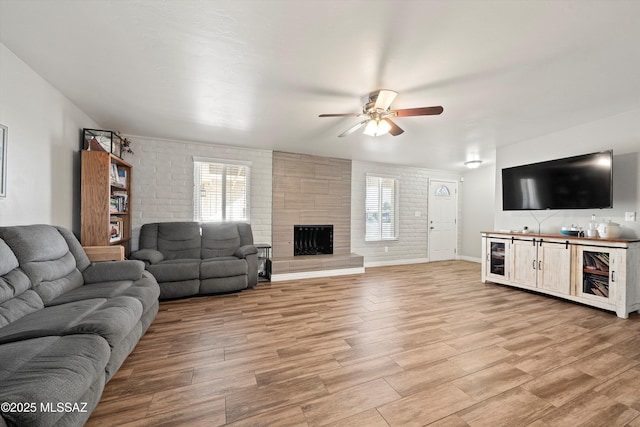 living room featuring a tile fireplace, plenty of natural light, and light wood-type flooring