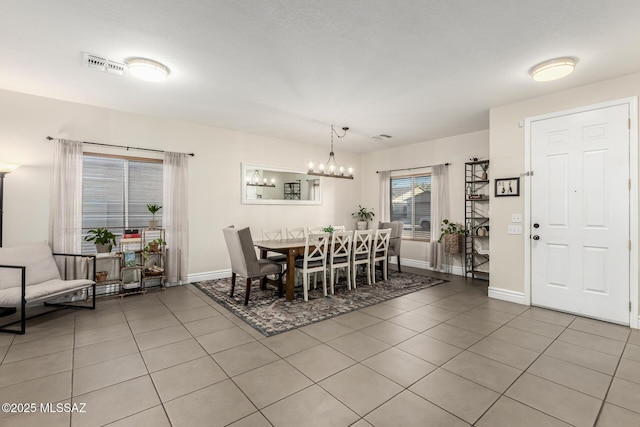 dining space with a chandelier and tile patterned flooring