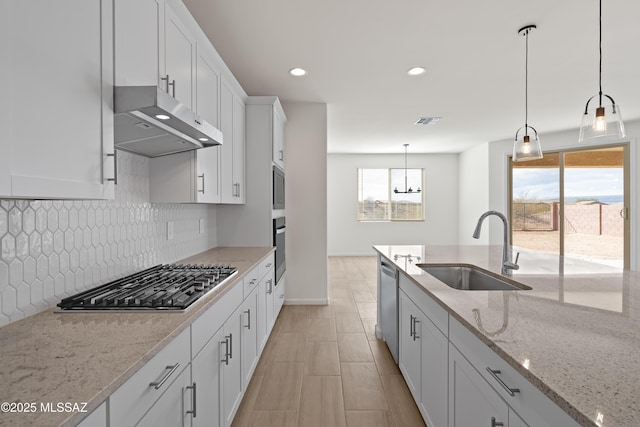 kitchen with light stone counters, stainless steel appliances, sink, and white cabinets