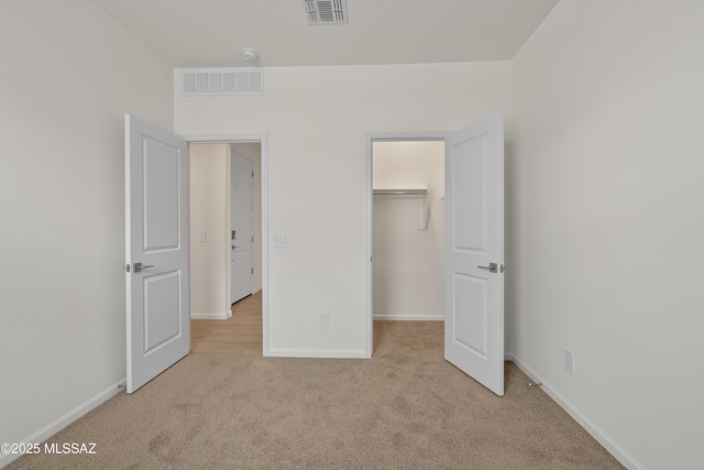 unfurnished bedroom featuring light carpet, a spacious closet, and a closet