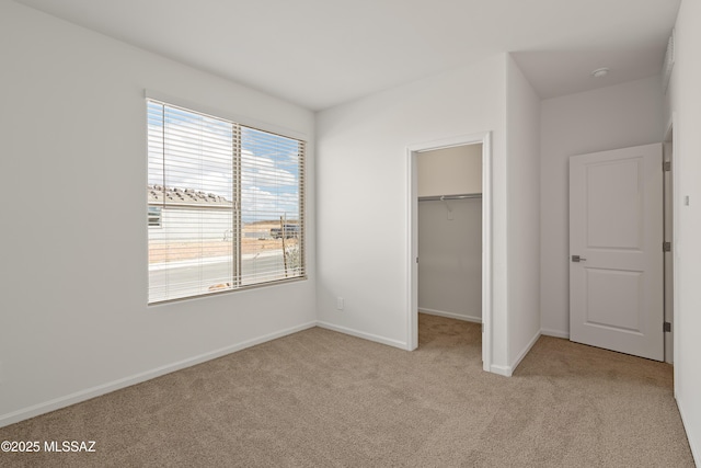 unfurnished bedroom featuring light carpet, a walk in closet, and a closet