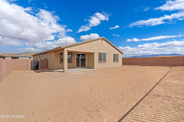 back of property with a mountain view and a patio area