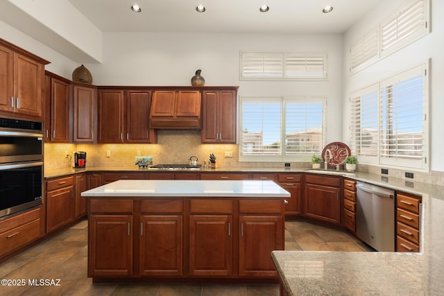 kitchen featuring tasteful backsplash, appliances with stainless steel finishes, light countertops, and a center island