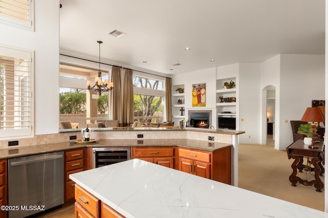 kitchen featuring visible vents, brown cabinetry, dishwasher, wine cooler, and decorative light fixtures