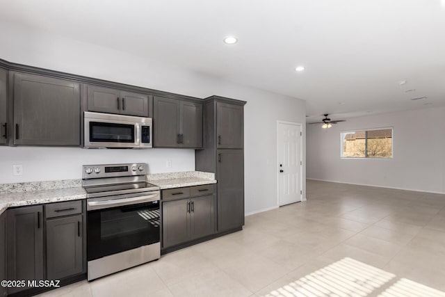 kitchen with light stone countertops, dark brown cabinets, stainless steel appliances, and ceiling fan