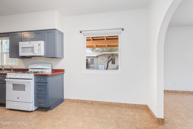 kitchen featuring light tile patterned flooring, white appliances, and sink