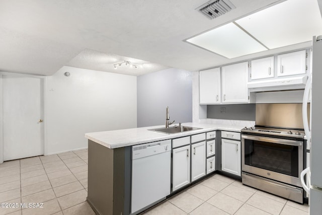 kitchen with sink, appliances with stainless steel finishes, white cabinets, light tile patterned flooring, and kitchen peninsula