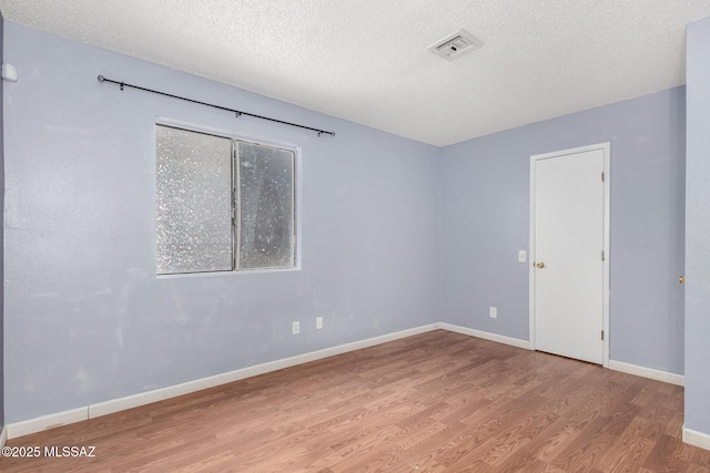 unfurnished room with light hardwood / wood-style floors and a textured ceiling