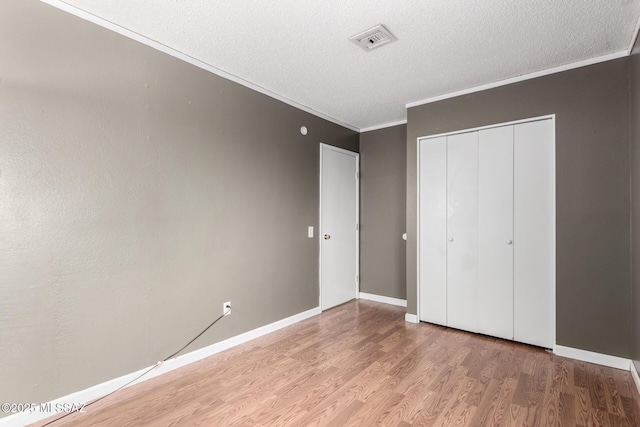 unfurnished bedroom featuring a closet, ornamental molding, wood-type flooring, and a textured ceiling