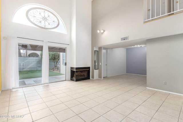 unfurnished living room featuring light tile patterned floors, a towering ceiling, and a fireplace