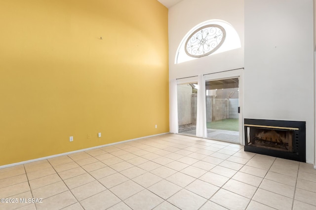 unfurnished living room featuring light tile patterned flooring and high vaulted ceiling