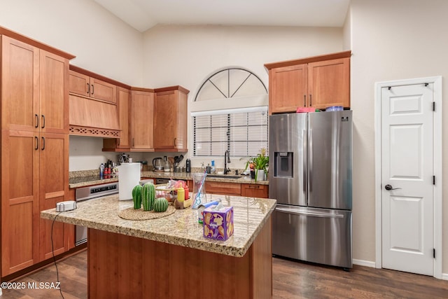 kitchen featuring sink, custom exhaust hood, light stone counters, a center island, and stainless steel fridge