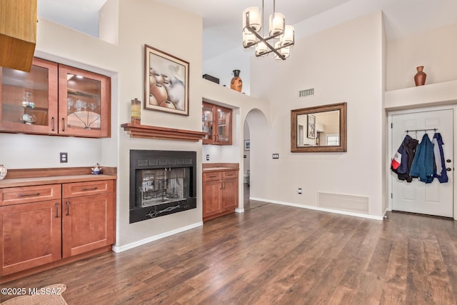 unfurnished living room featuring dark wood-type flooring, an inviting chandelier, and high vaulted ceiling