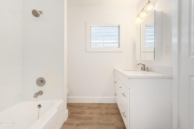 bathroom with wood-type flooring, tiled shower / bath combo, and vanity