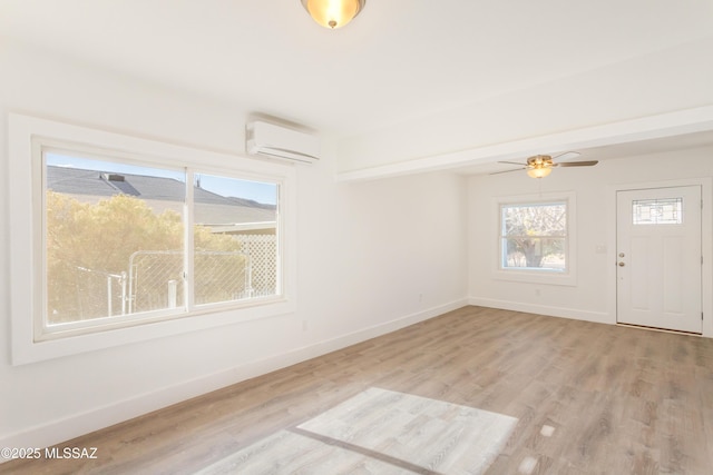interior space with ceiling fan, a wall mounted AC, and light wood-type flooring