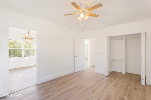 unfurnished bedroom featuring ceiling fan with notable chandelier and light hardwood / wood-style floors