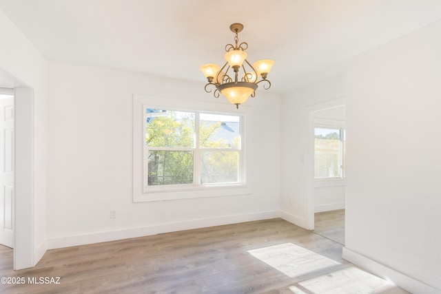 unfurnished dining area with plenty of natural light, a chandelier, and light wood-type flooring