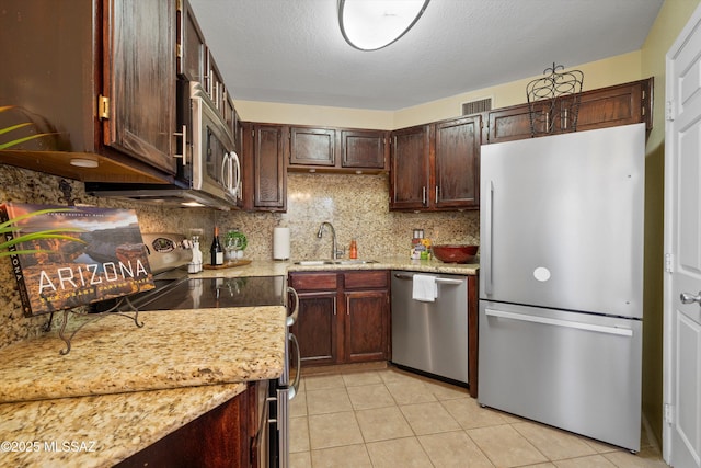 kitchen featuring appliances with stainless steel finishes, sink, decorative backsplash, light tile patterned floors, and dark brown cabinetry