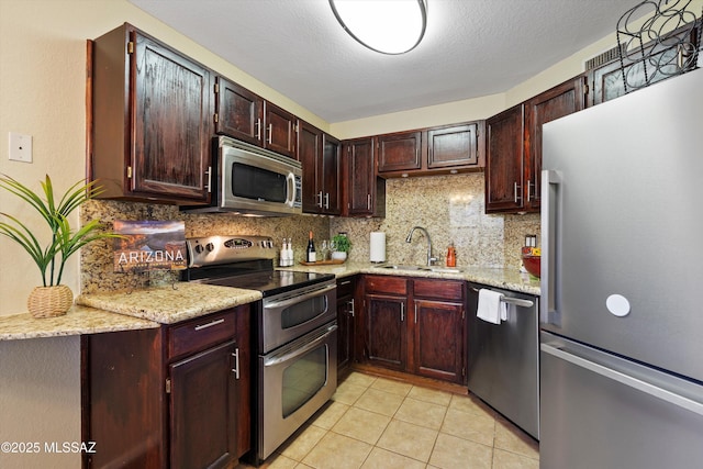 kitchen featuring light tile patterned flooring, tasteful backsplash, sink, stainless steel appliances, and light stone countertops