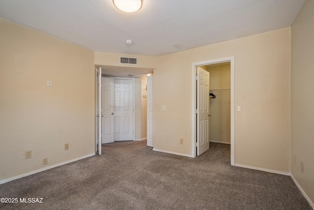 unfurnished bedroom with a walk in closet and carpet floors