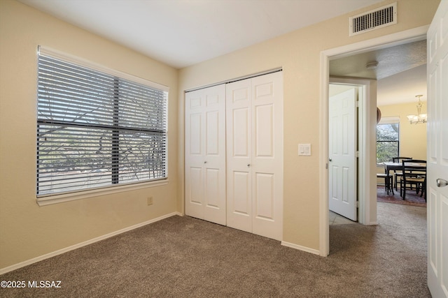 bedroom featuring a notable chandelier, dark carpet, and a closet