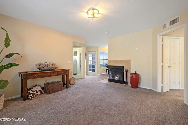 carpeted living room featuring a tile fireplace