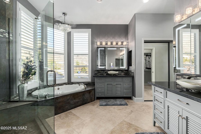 bathroom featuring vanity, tiled bath, and a chandelier