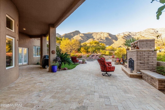 view of patio with an outdoor brick fireplace, a mountain view, and french doors