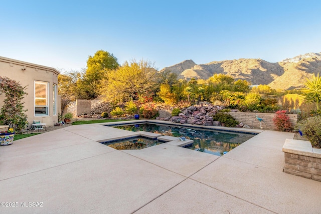 view of pool featuring a mountain view, a patio, and an in ground hot tub