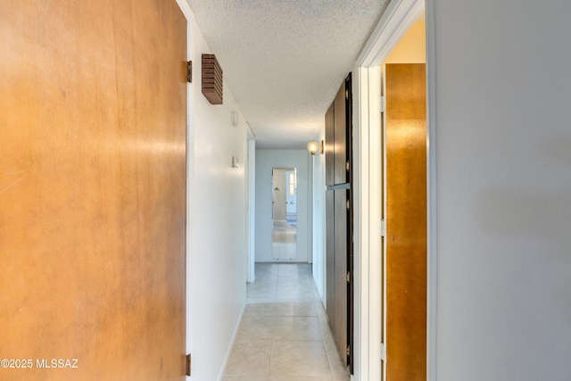 corridor with a textured ceiling and light tile patterned floors