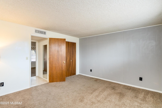 unfurnished bedroom featuring light carpet, a closet, and a textured ceiling