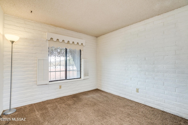 spare room featuring brick wall, a textured ceiling, and carpet flooring