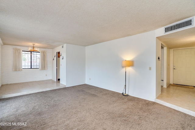 unfurnished room with light carpet, a textured ceiling, and an inviting chandelier